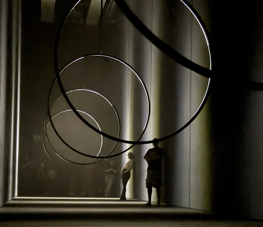 In the background, a woman casually leaning against a wall. In the foreground, many hoops.